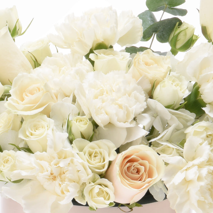 Elegant white and blush rose bouquet with lush greenery, soft lighting.