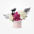 Pink cylinder holds vibrant pink roses and white hydrangeas, accented by silver wings and graduation cap.