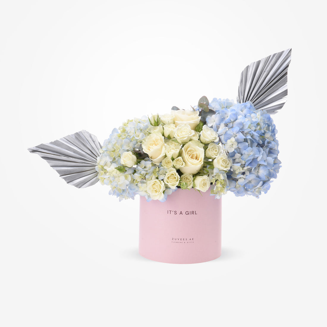 Pink box holds creamy roses and blue hydrangeas, accented with silver fan wings.