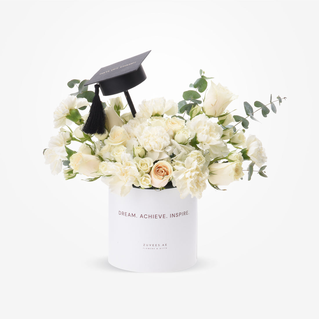 White roses and eucalyptus in sleek box topped with graduation cap.