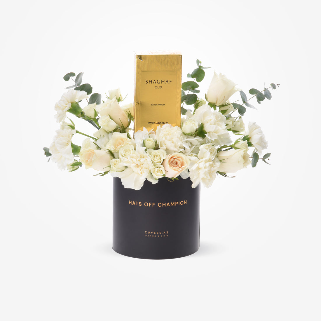 Elegant white floral arrangement in black cylinder with gold "Hats Off Champion" text and Shaghaf Oud perfume.