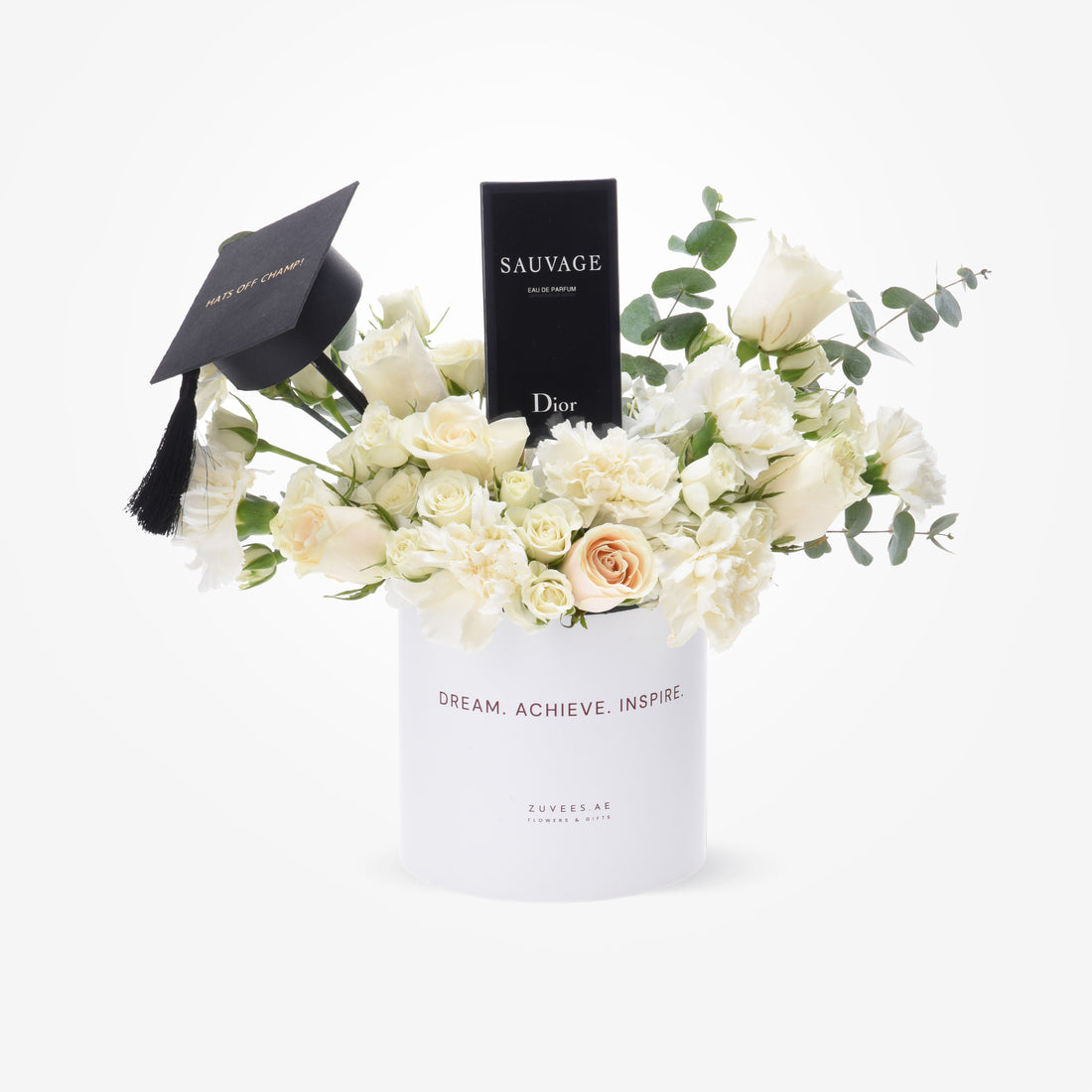 White roses and eucalyptus in sleek white vase with graduation cap and Dior perfume.