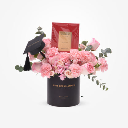 Pink roses and carnations in black graduation-themed vase with luxury perfume.