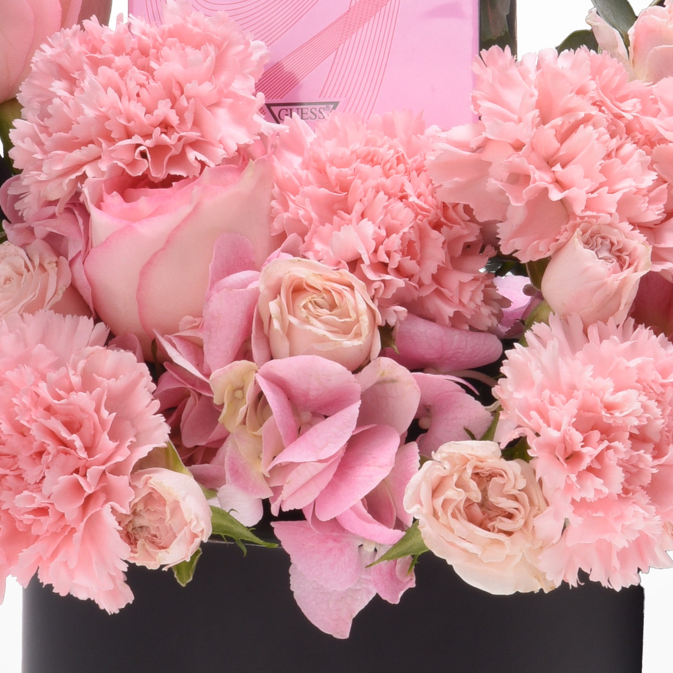 Soft pink carnations and roses in sleek black vase with branded pink box.