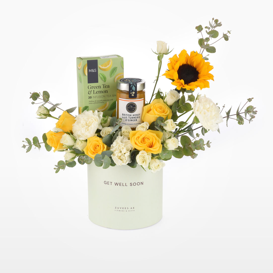 Pastel green vase holds vibrant yellow roses, sunflower, and white blooms with tea and honey.