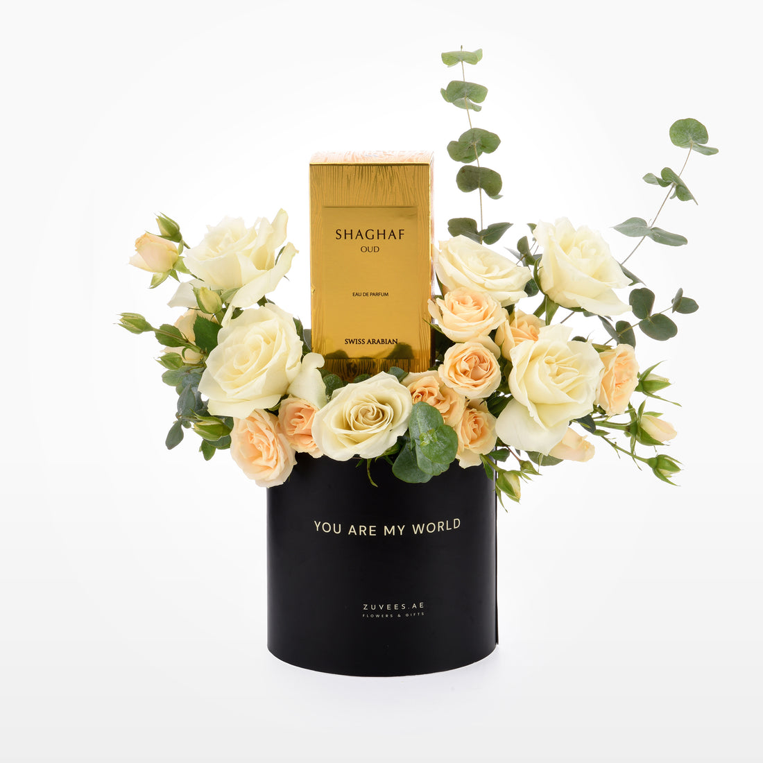 Elegant black vase with "You Are My World" text, holding cream roses and eucalyptus, centered with a gold Shaghaf Oud perfume box.