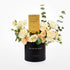Elegant black vase with "You Are My World" text, holding cream roses and eucalyptus, centered with a gold Shaghaf Oud perfume box.