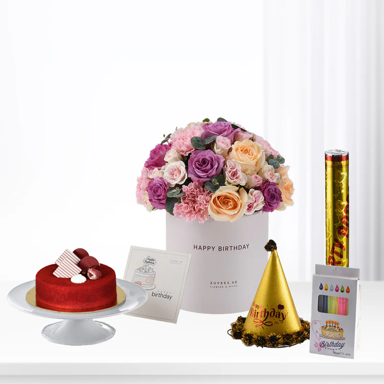 Vibrant pink, purple, and peach roses in white box with birthday cake, party hat, and confetti.