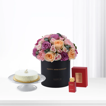 Elegant anniversary bouquet, cake, and perfume set in minimalist white setting.