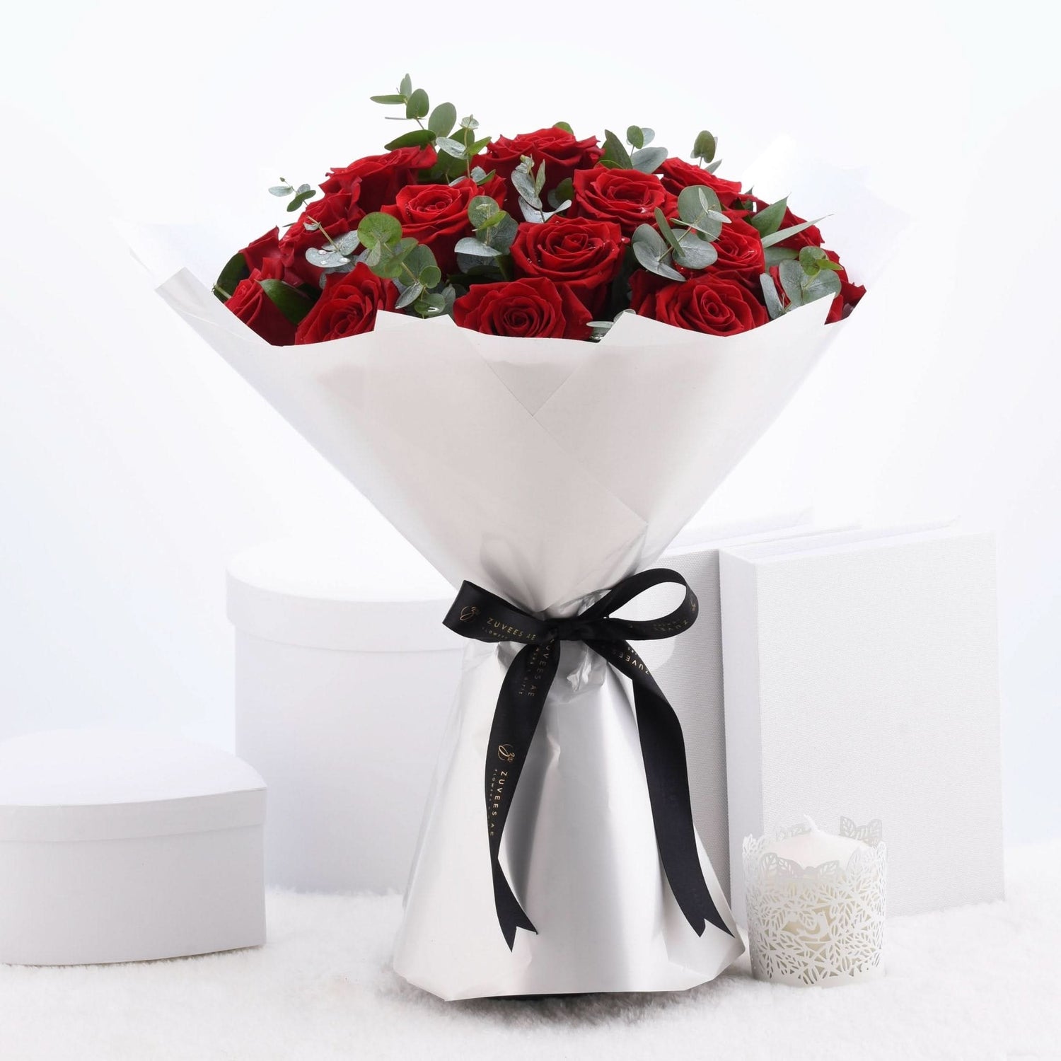 Vibrant red roses wrapped in white paper with black ribbon, elegant gift presentation.