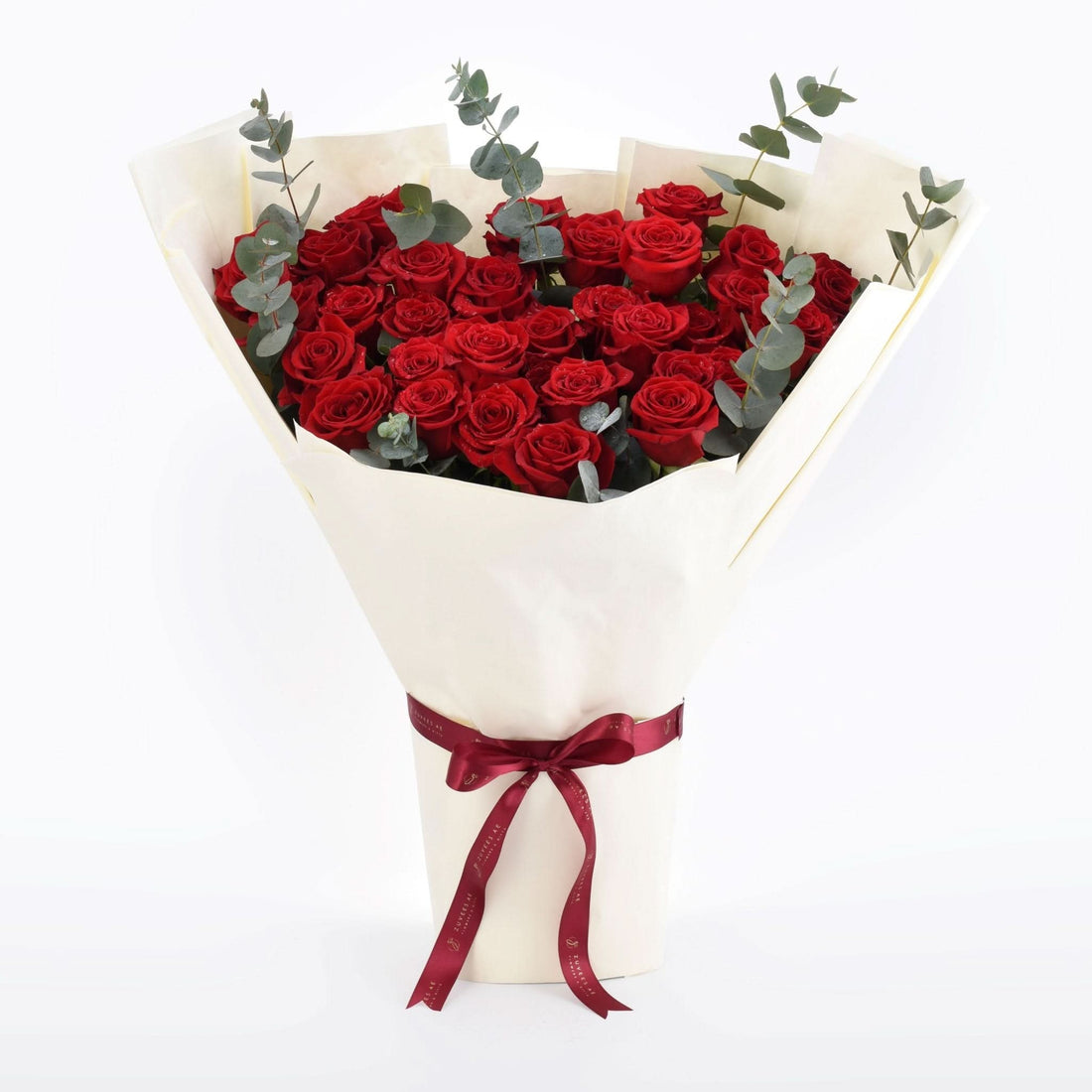 Vibrant red roses with eucalyptus, cream wrap, burgundy ribbon bow, elegant romantic gift bouquet.