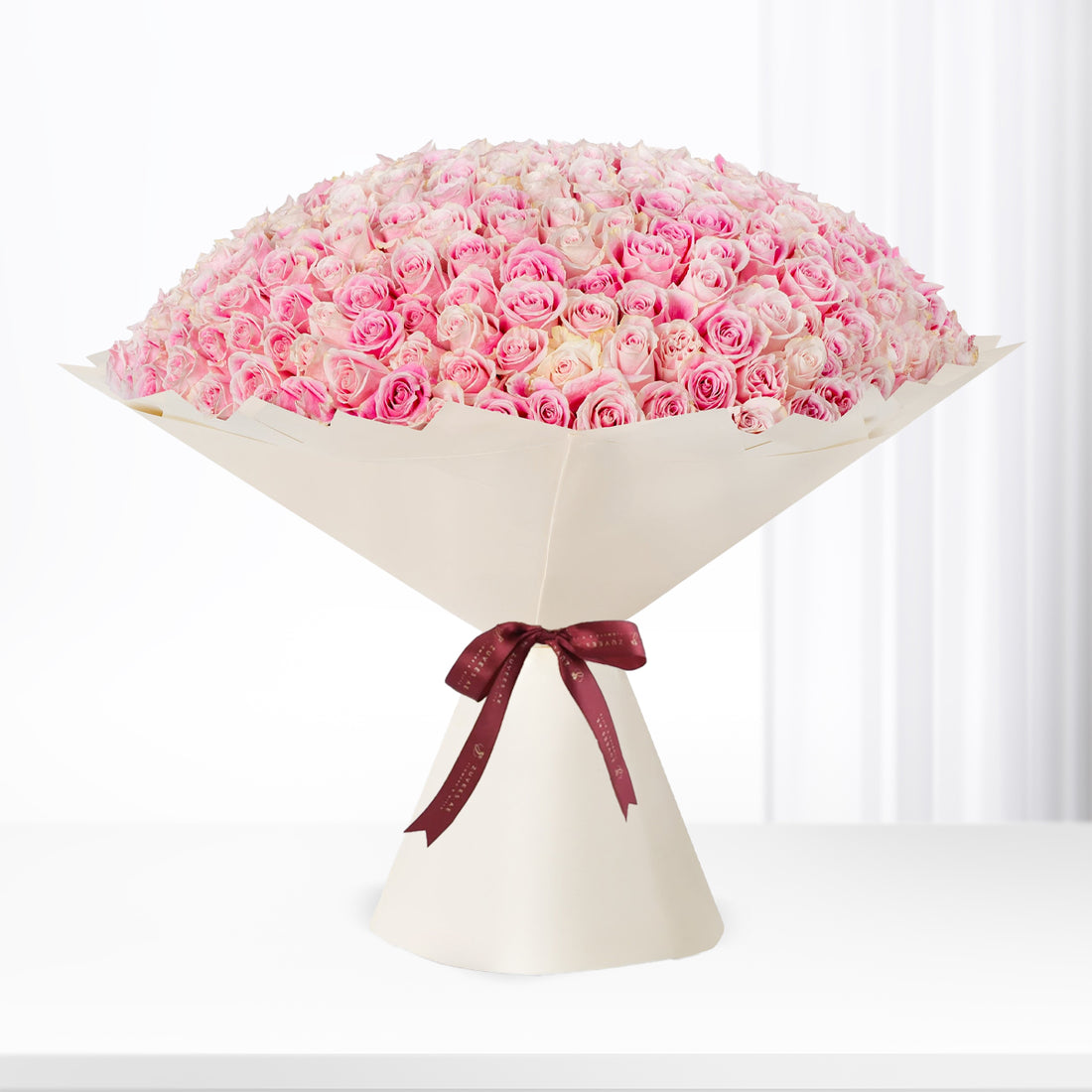 Vast dome of blush-pink roses, elegantly wrapped in cream paper with burgundy ribbon.