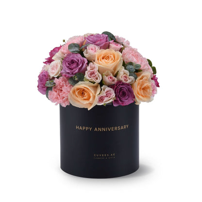 Elegant black box with "Happy Anniversary" text, filled with pink, purple, and peach roses.
