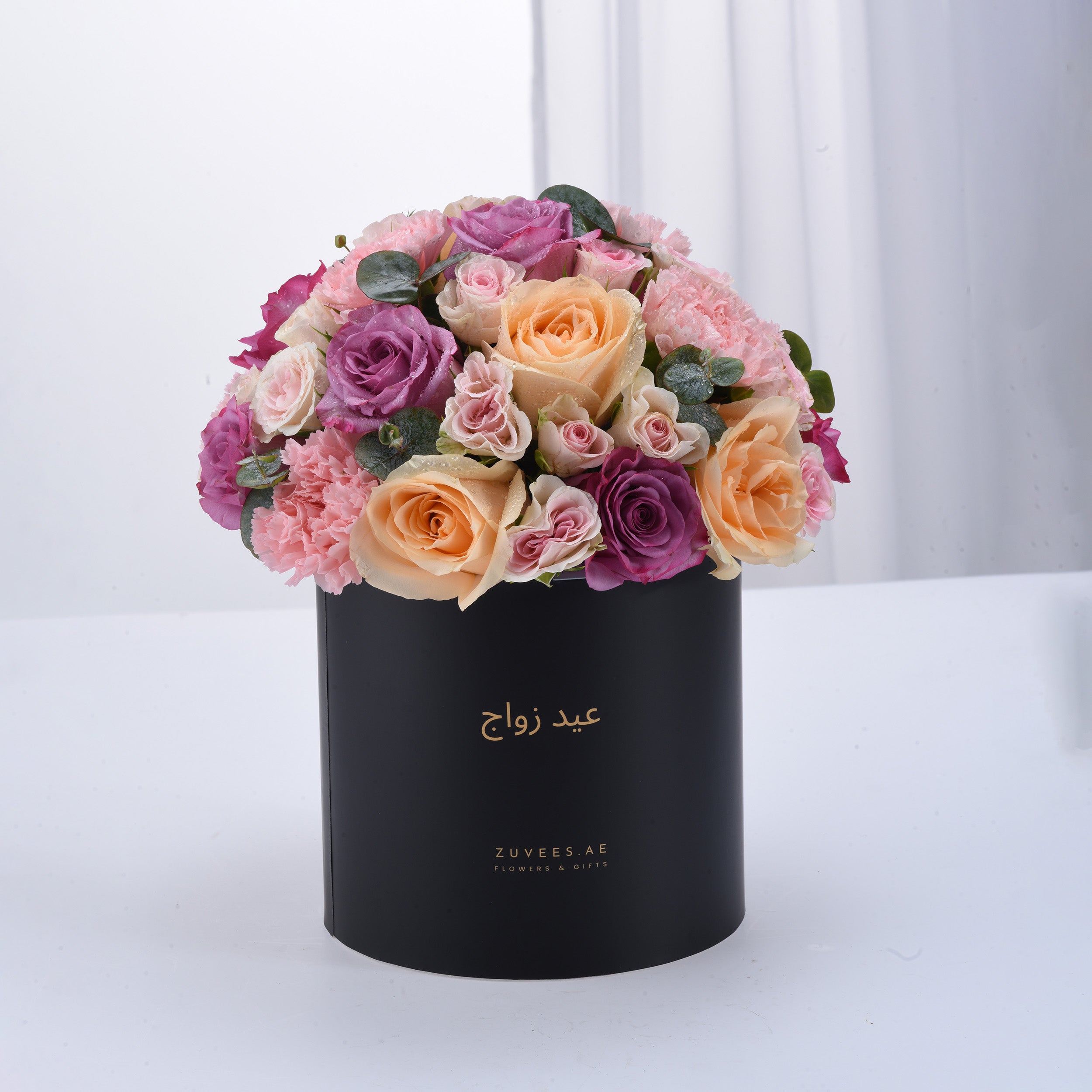 Elegant black box filled with lush pink, purple, and peach roses and carnations.
