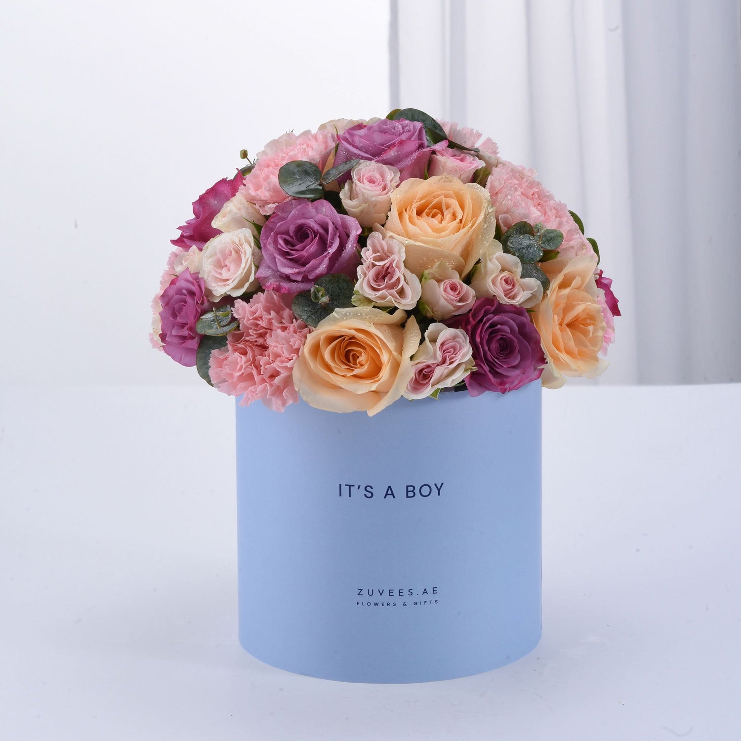 Pastel pink, purple, and peach roses in light blue box reading "It&