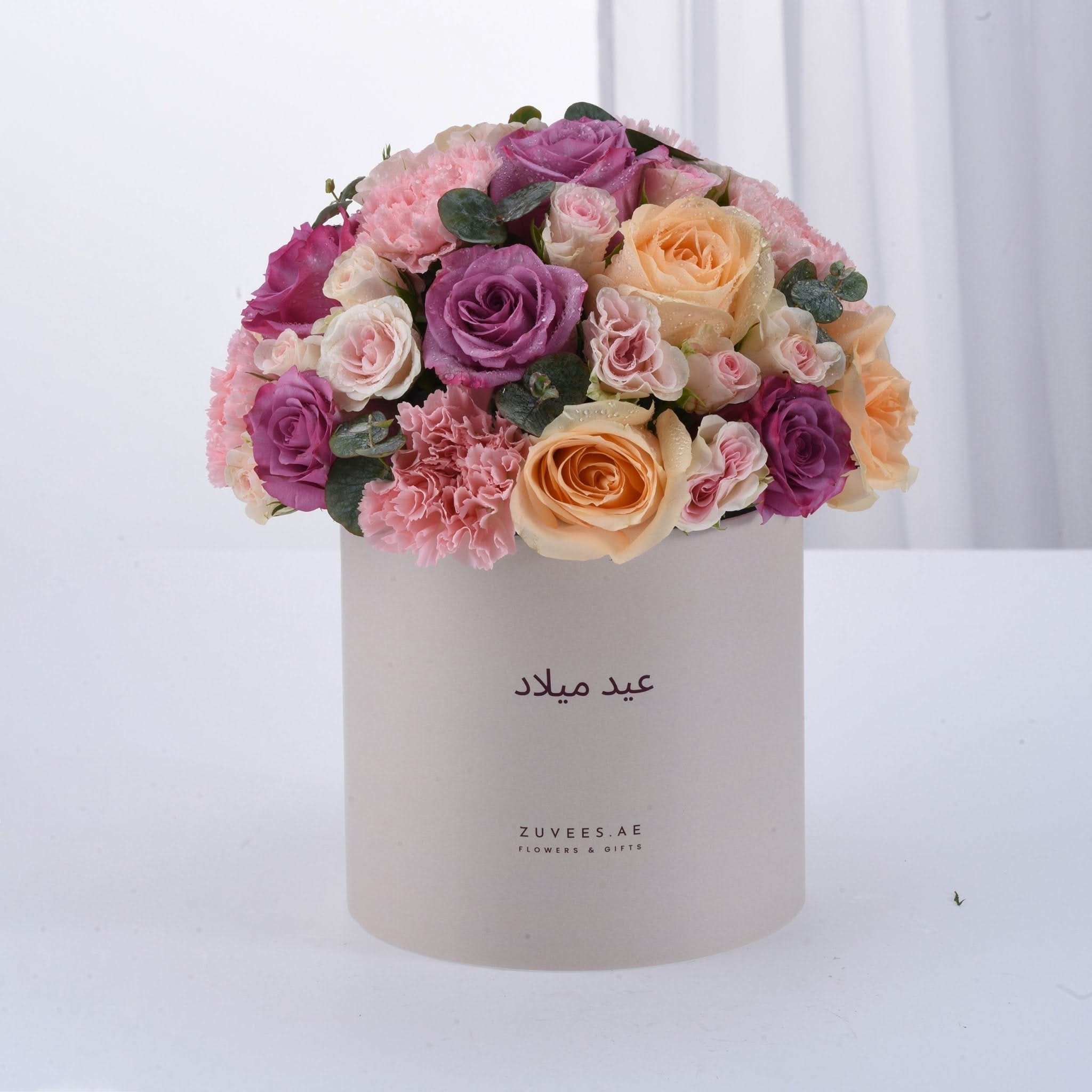 Pastel pink, purple, and peach roses in elegant white box with Arabic text.