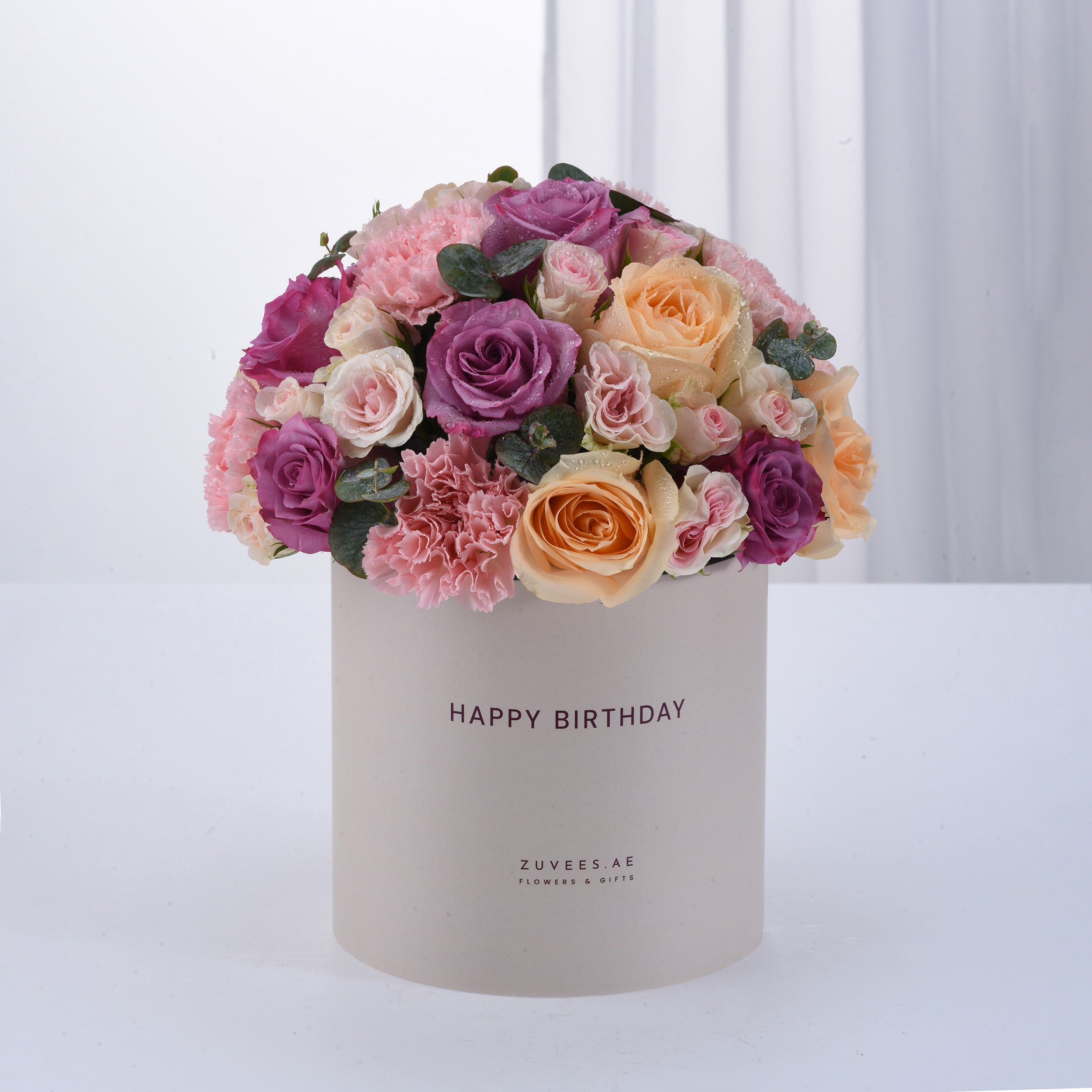 Pastel pink, purple, and peach roses with carnations in a white "Happy Birthday" box.