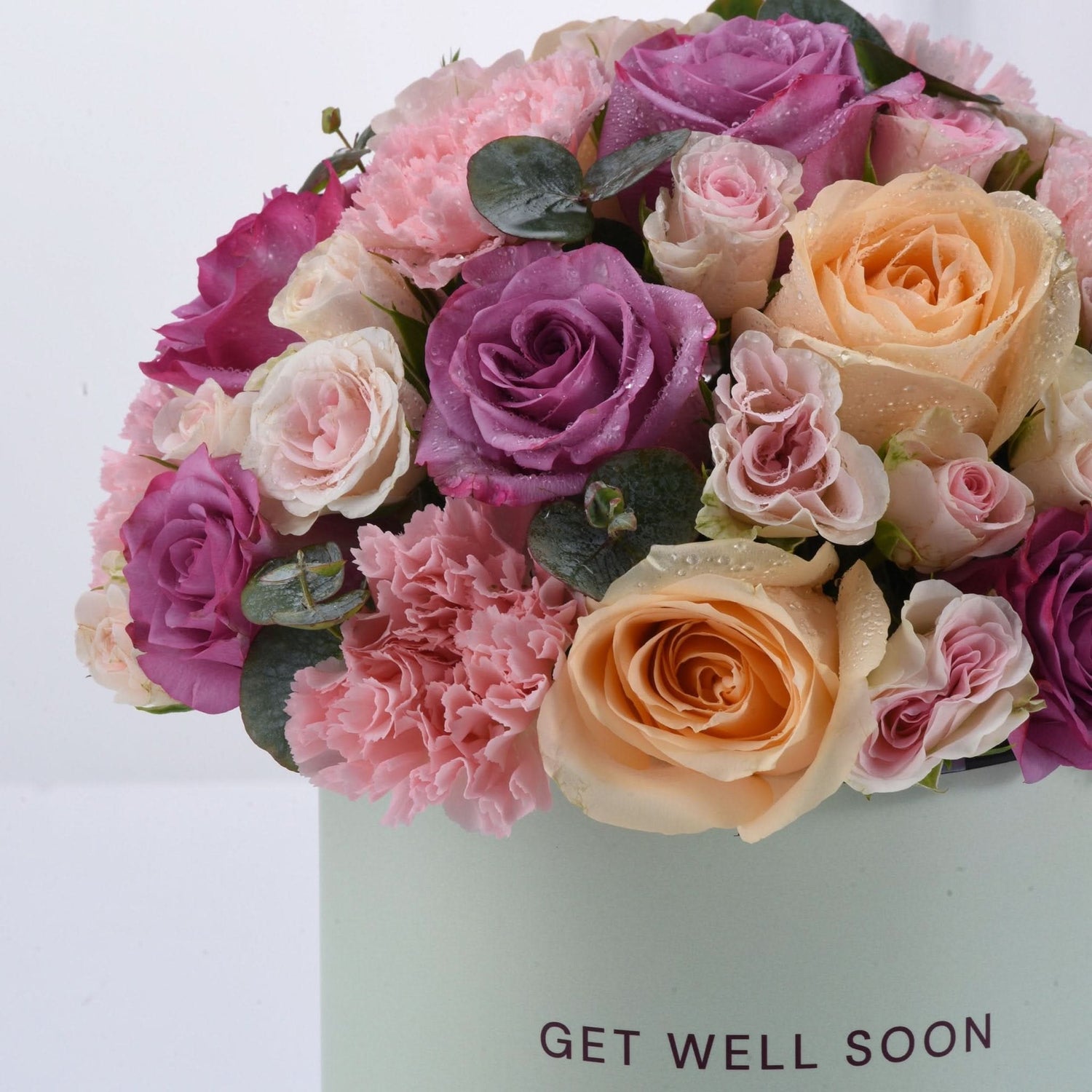 Pastel pink, purple, and peach roses with dewdrops in "Get Well Soon" box.