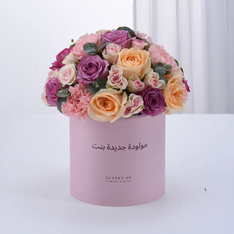 Soft pink box overflowing with vibrant roses and carnations, perfect baby girl gift.