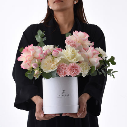 Elegant white box holds blush pink and cream roses, carnations, and eucalyptus.