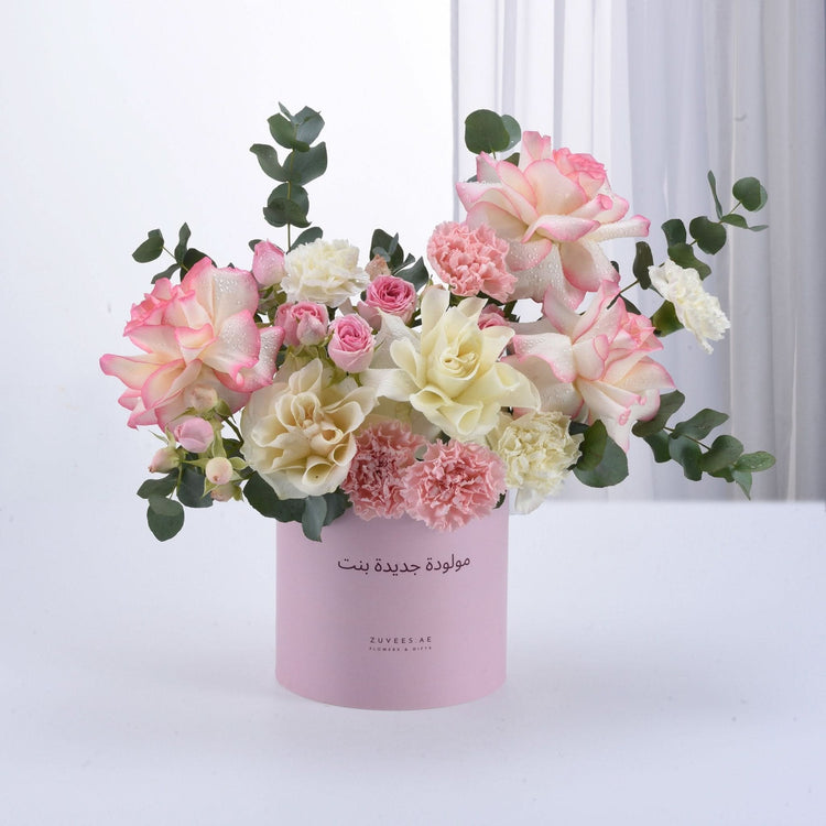 Soft pink and white roses, carnations, eucalyptus in pastel pink cylinder with Arabic birthday message.