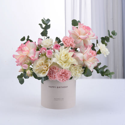 Pastel pink and cream roses with carnations in a "Happy Birthday" cylinder vase.
