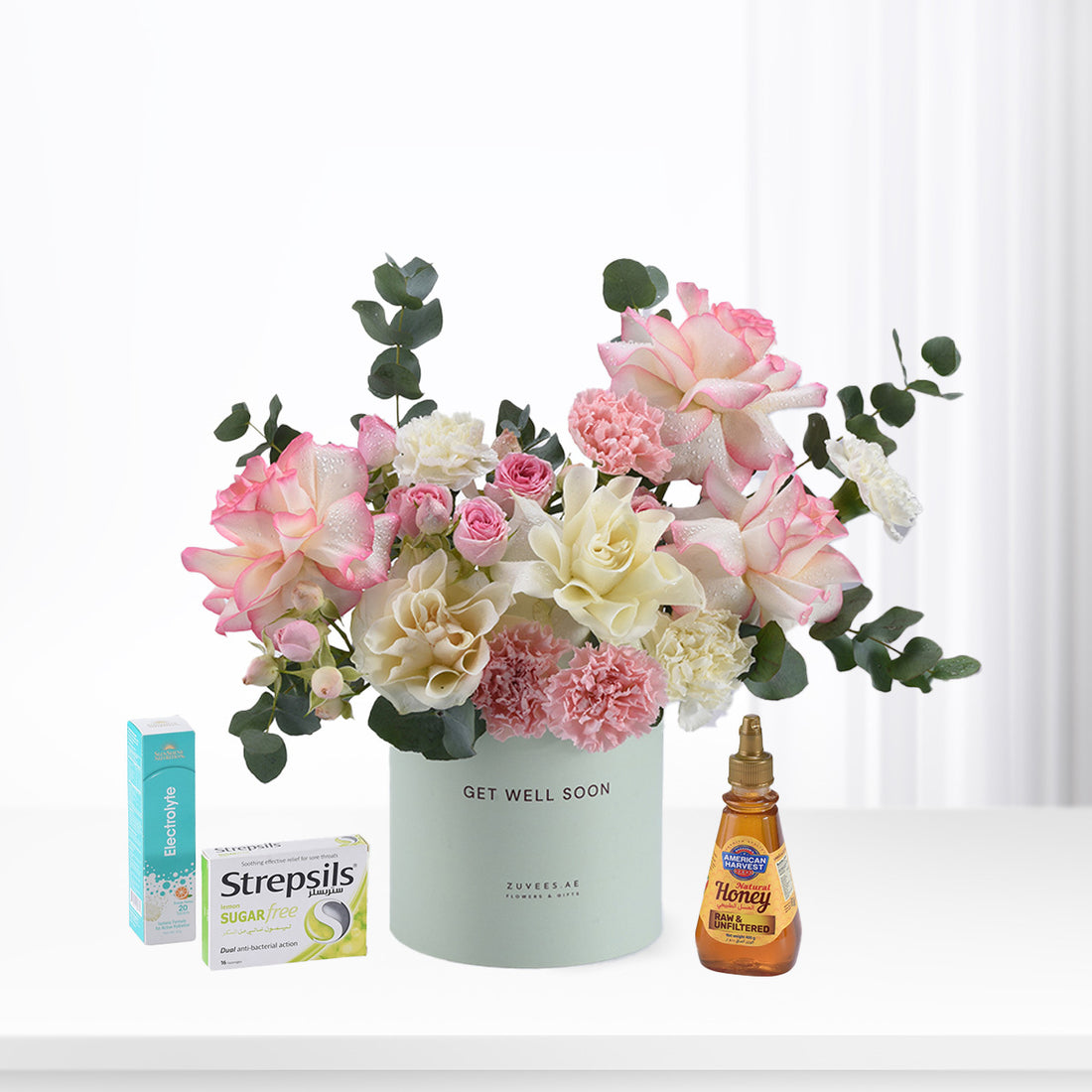 Pastel pink and white roses with eucalyptus, honey, and throat soothers in mint vase.