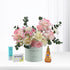 Pastel pink and white roses with eucalyptus, honey, and throat soothers in mint vase.