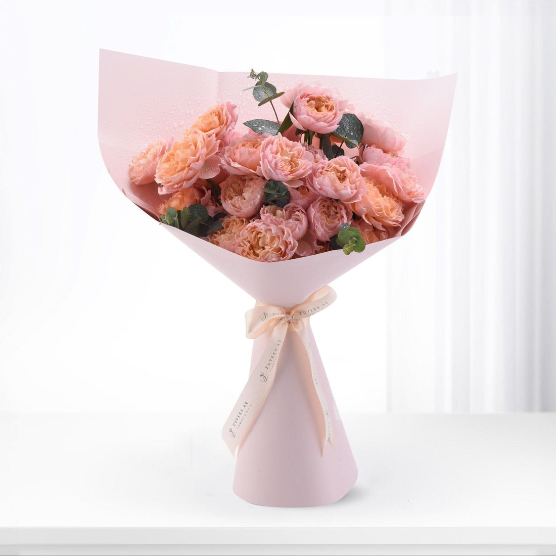 Pink peony bouquet wrapped in blush paper, tied with ribbon, dew-kissed petals, elegant gift.