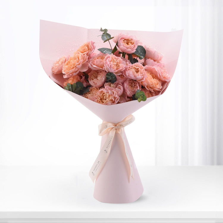Pink peony bouquet wrapped in blush paper, tied with ribbon, dew-kissed petals, elegant gift.