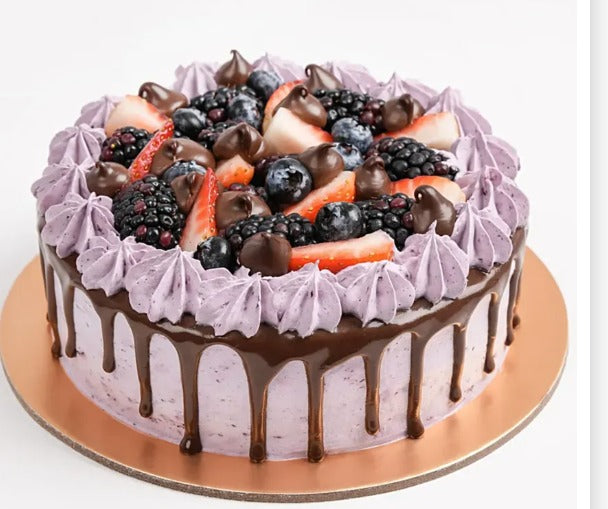 Purple berry cake with chocolate drizzle and fresh fruit topping.