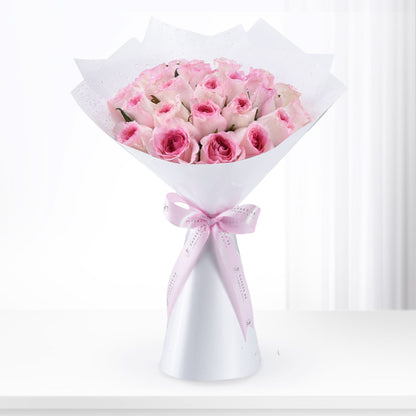 Pink roses in white wrap with dewdrops, tied with branded ribbon, elegant gift bouquet.