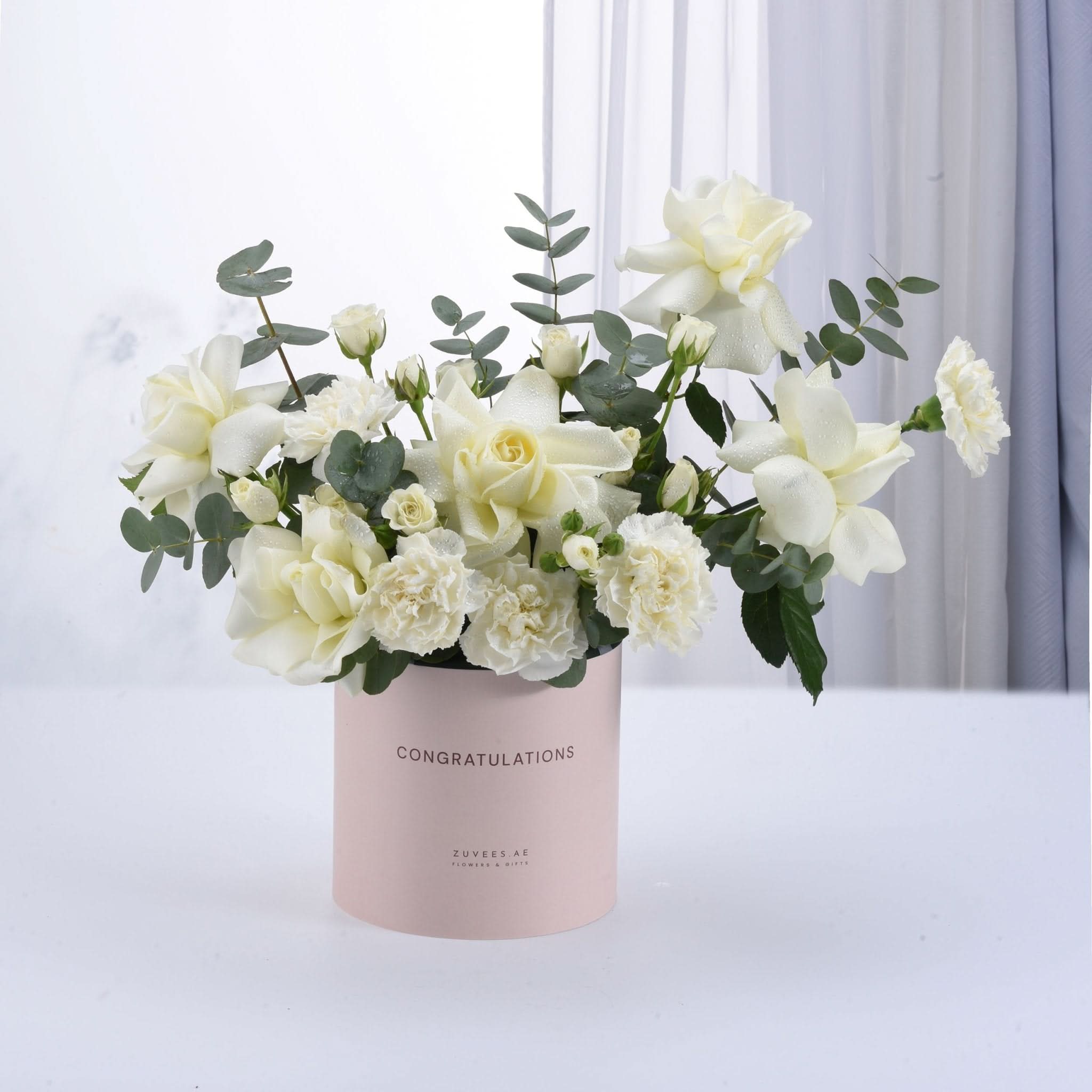 Elegant white roses and carnations in a pink "Congratulations" cylinder gift box.
