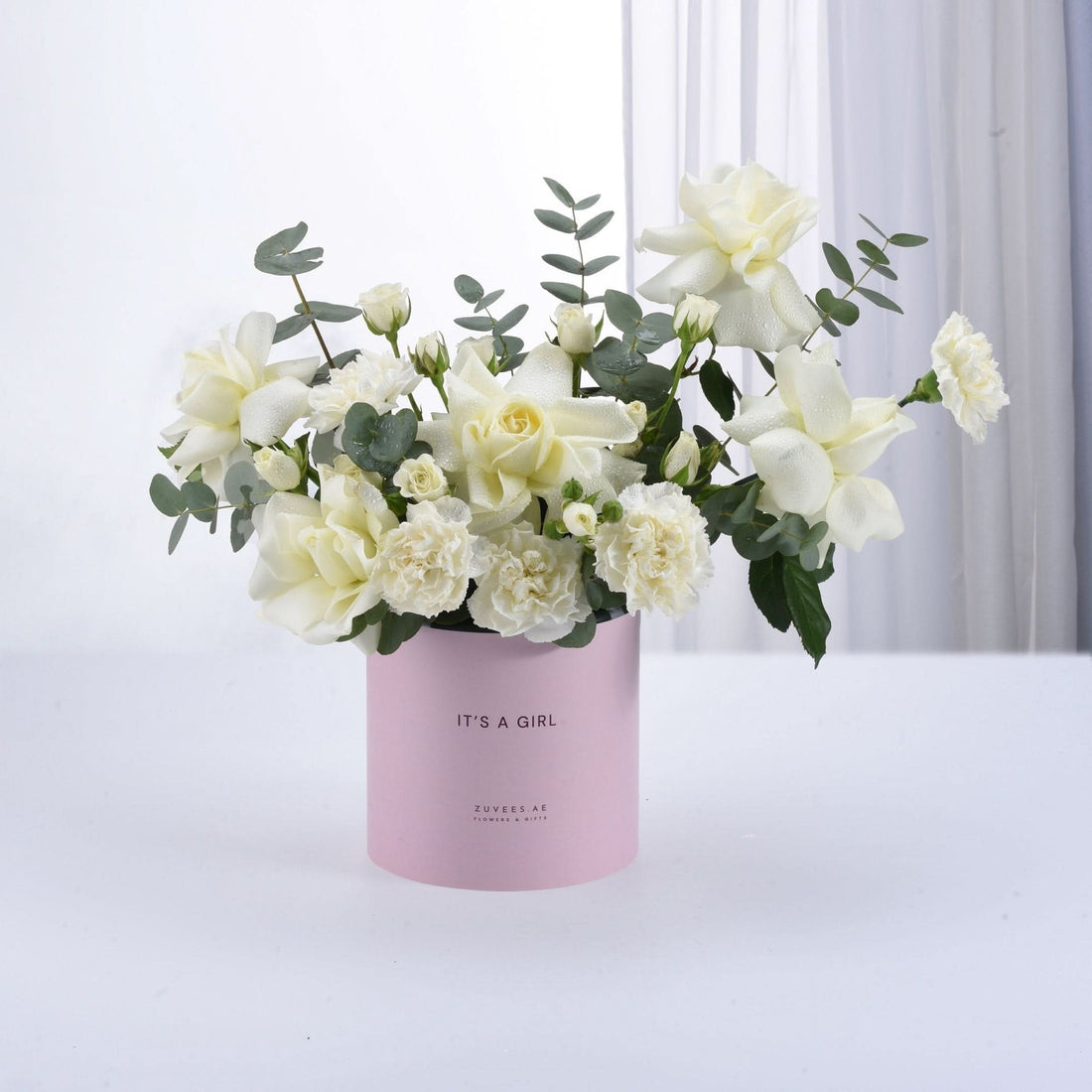 Soft white roses and eucalyptus in a pink "It&