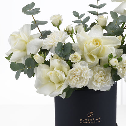 Elegant white roses and carnations with dewdrops in sleek black vase.