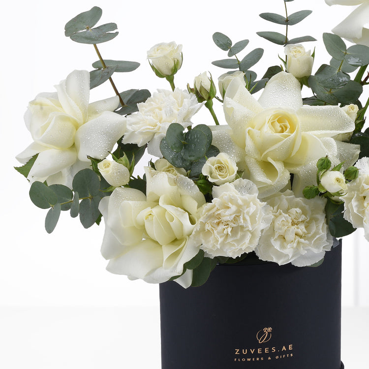 Elegant white roses and carnations with dewdrops in sleek black vase.