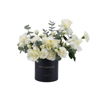 Elegant white roses and carnations in matte black "Happy Anniversary" vase.
