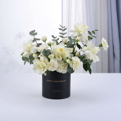 Elegant white roses and eucalyptus in matte black "Happy Anniversary" vase.