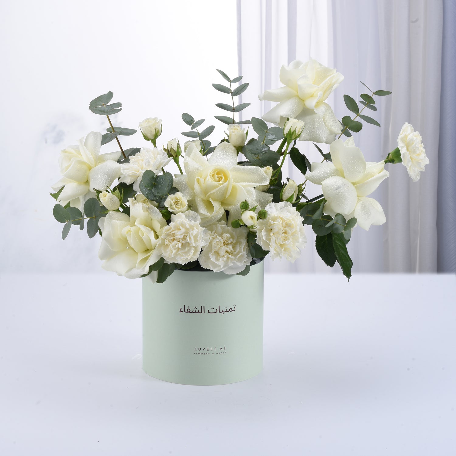 Elegant white roses and carnations in mint-green cylindrical gift box.