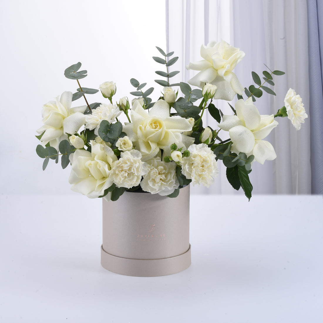 Elegant white rose and carnation arrangement in a matte silver hat box.