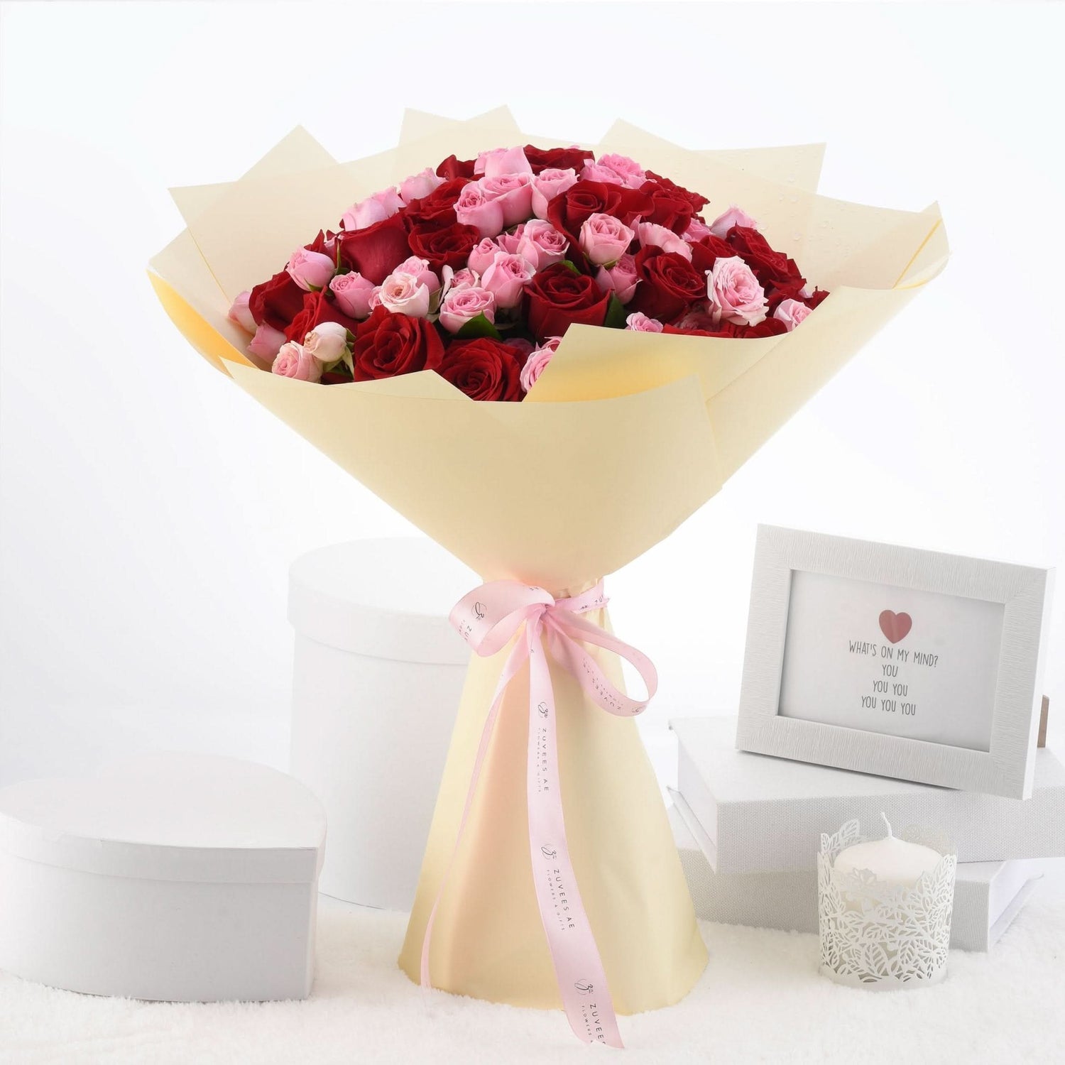 Vibrant red and pink roses wrapped in cream paper with pink ribbon.