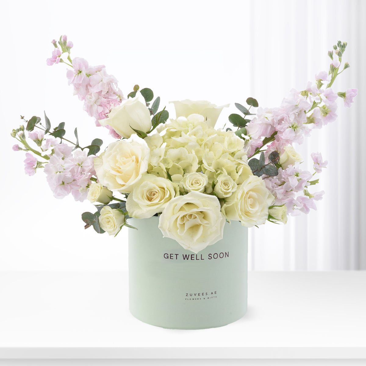 Pastel mint box holds creamy roses, lavender blooms, and eucalyptus—“Get Well Soon” message.