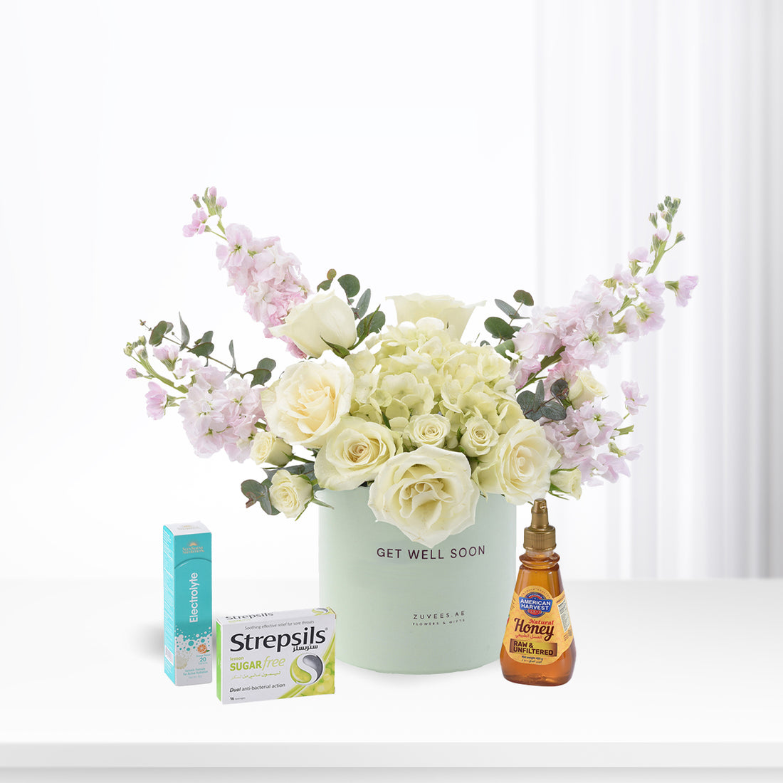 Pastel floral arrangement with honey, throat lozenges, and electrolyte for recovery.