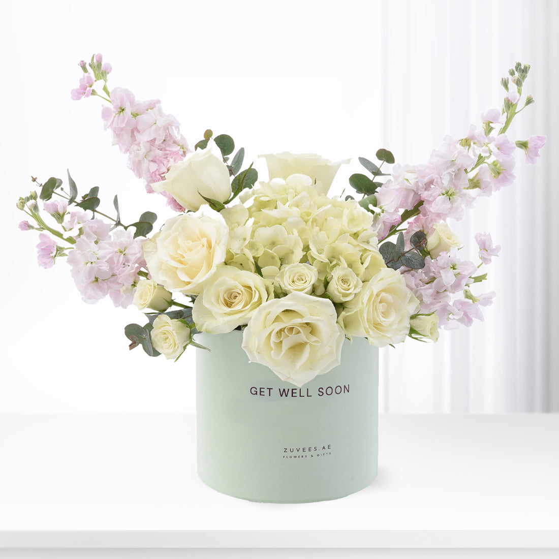 Pastel floral arrangement in mint "Get Well Soon" vase with roses and eucalyptus.
