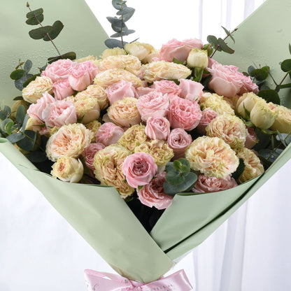 Soft pink and cream roses wrapped in sage green paper with delicate eucalyptus accents.