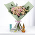 Soft pink and cream roses wrapped in sage green paper, tied with pink ribbon, beside Strepsils and honey.