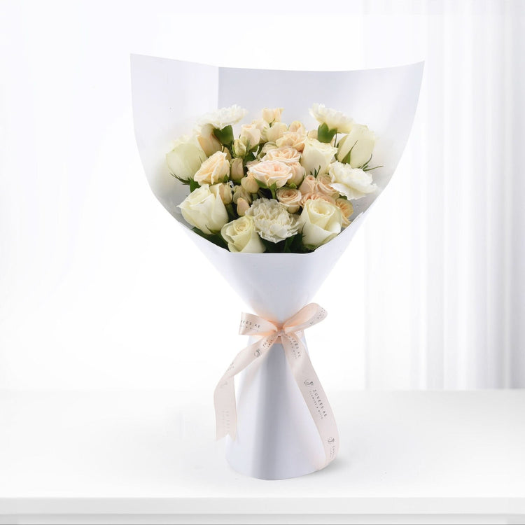 Elegant white rose bouquet wrapped in crisp paper, tied with blush ribbon, perfect for gifts.