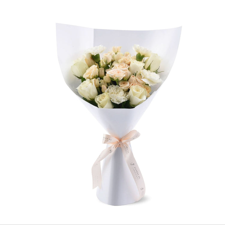 Elegant white and blush rose bouquet wrapped in crisp white paper with branded ribbon.