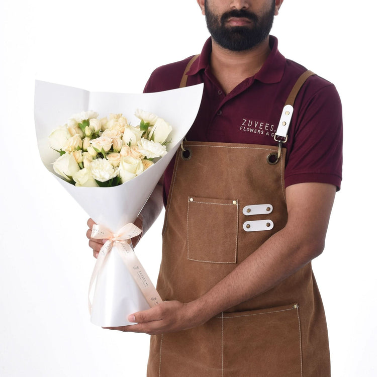 Florist presents elegant white rose bouquet in crisp white paper and blush ribbon.