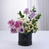Elegant lavender, pink, and white roses in sleek black box with greenery.